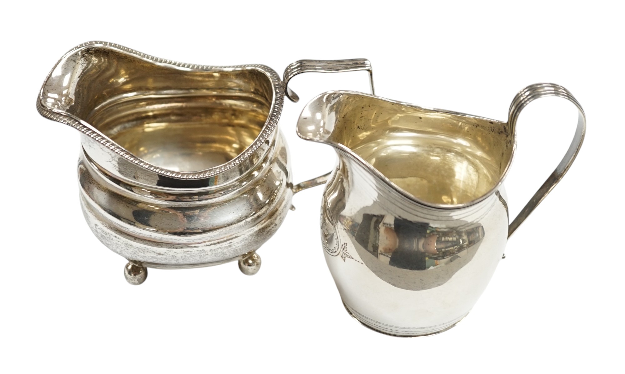 A George III silver helmet shaped cream jug, London, 1806, 10.2cm, together with another George III silver cream jug(repair). Condition - poor to fair